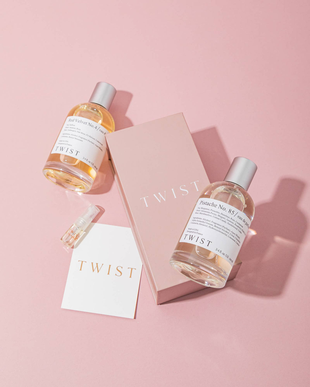 A Bang No. 91 perfume bottle, a small sample vial, a card, and a pink House of Twist box are arranged on a pink background. The bottle is labeled Bang No. 91—crafted as a long-lasting perfume for women inspired by timeless French fragrance traditions and made with vegan, cruelty-free ingredients.