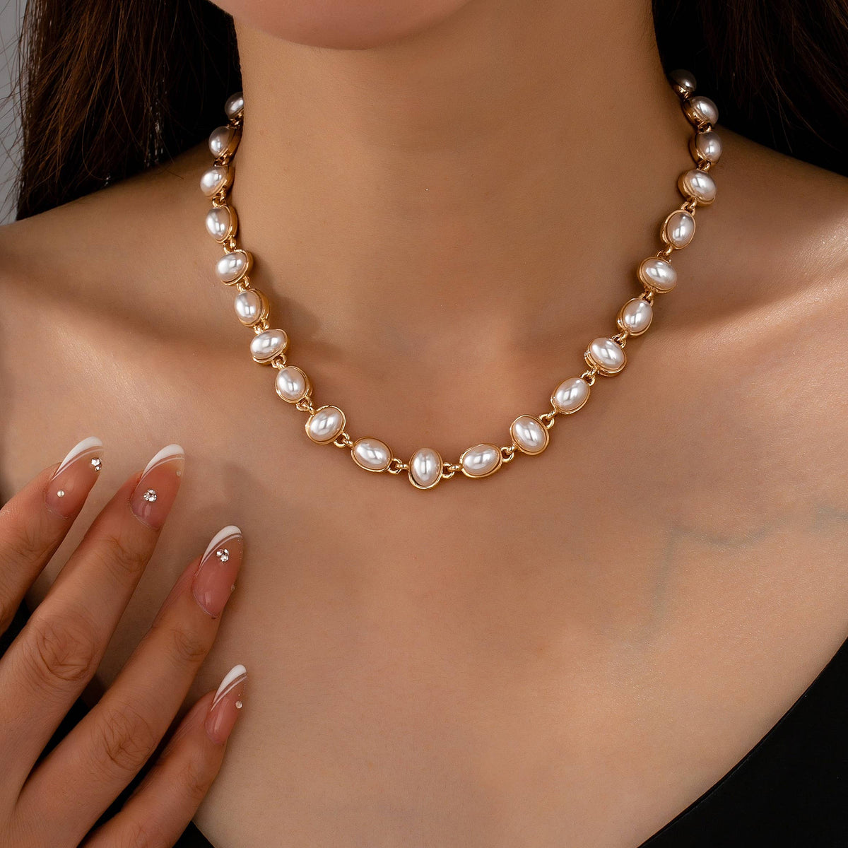 A JOSSLYN by wall to wall Oval Pearl Link Necklace featuring a gold chain with a series of oval-shaped white pearls, worn around the neck.