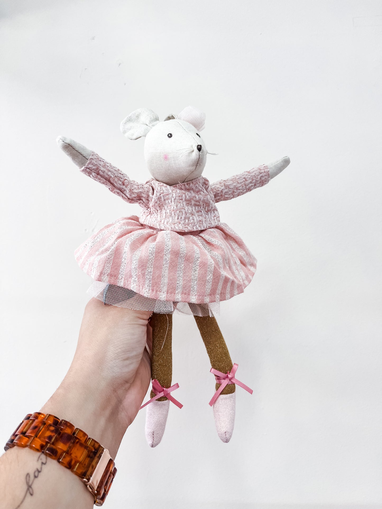 A hand holds the Tiny Tot Bundles Little Dancer Mice Stuffed Animal, featuring a pink and white striped dress with tulle skirt, brown legs, pink ballet shoes, a small pink hat, and outstretched arms.