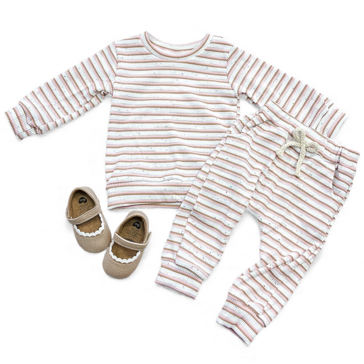 The Stripe Meadow Joggers Set by Tiny Tot Bundles features a long-sleeve striped top and pastel joggers, paired with beige shoes with white scalloped trim, all shown on a white background.
