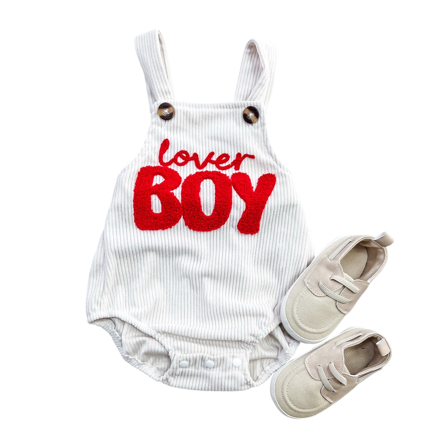 The Tiny Tot Bundles Lover Boy Romper is a white pinstriped baby outfit with “lover BOY” in red on the front, shown with light beige baby shoes on a white background.
