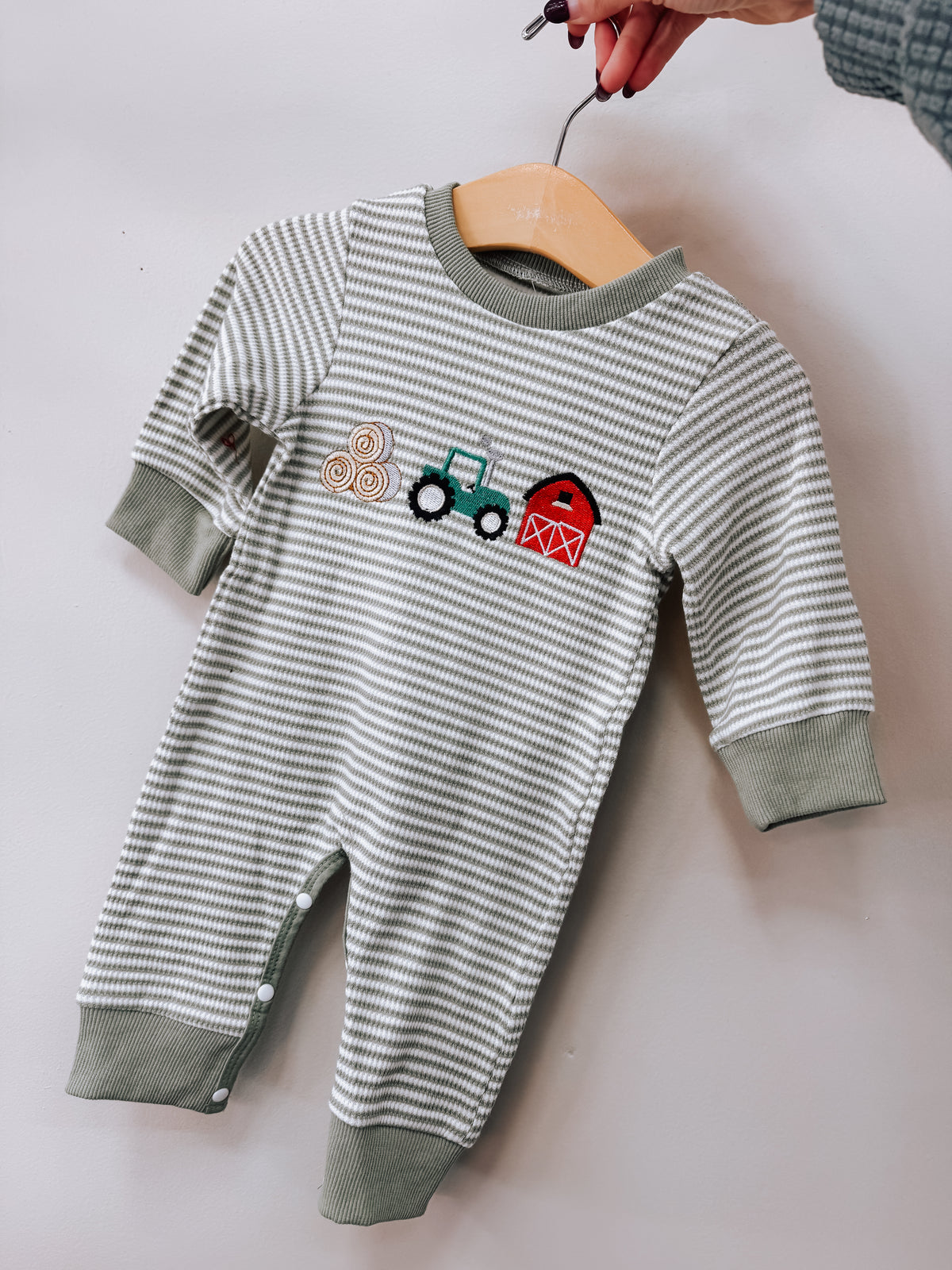 Tiny Tot Bundles Farm Friends Long Sleeve Romper with thin gray and white stripes, featuring an embroidered design of hay bales, a tractor, and a red barn on the chest.