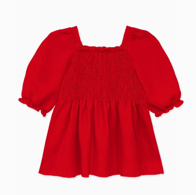 The Cutie Patootie Ruby Ruffle Smock Top is a bright red girls' top with a square neckline, smocked bodice, puffed elbow-length sleeves featuring ruffled hems, and is shown on a white background.