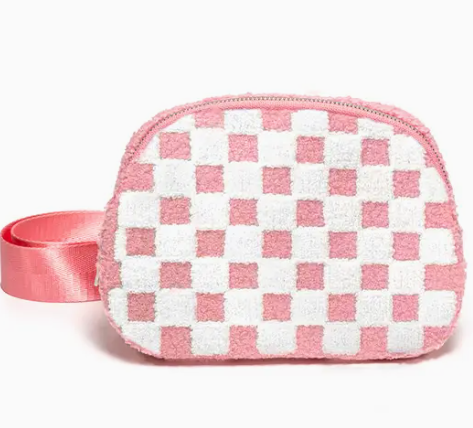 The Living Royal Checkered Cutie Belt Bag features a pink and white checkered pattern, fuzzy texture, and a wide pink wrist strap on the side.