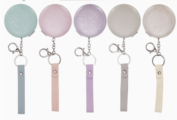 The Tiny Tot Bundles Pearlescent Compact Mirror Key Chain features five pastel colors—blue, pink, purple, gray, and off-white—with a keyring, lobster clasp, and matching faux leather strap.