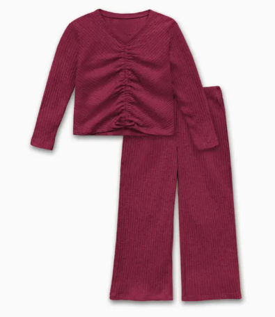 The Cutie Patootie Weekend Comfort Ruched Set, a burgundy ribbed knit pajama set with a long-sleeve ruched V-neck top and wide-leg pants, is laid flat on a white background.