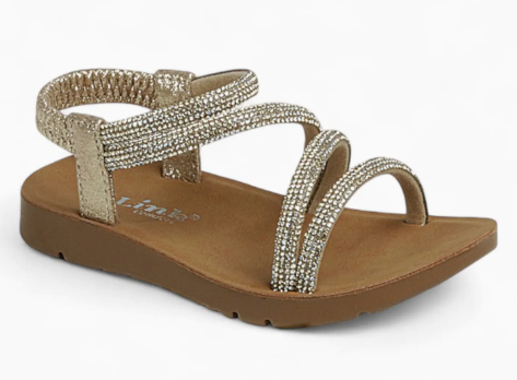 The Golden Glow Sandals by Fashion Emporio are children's gold strappy sandals featuring sparkling rhinestones, an elastic ankle strap, and a brown flat sole.