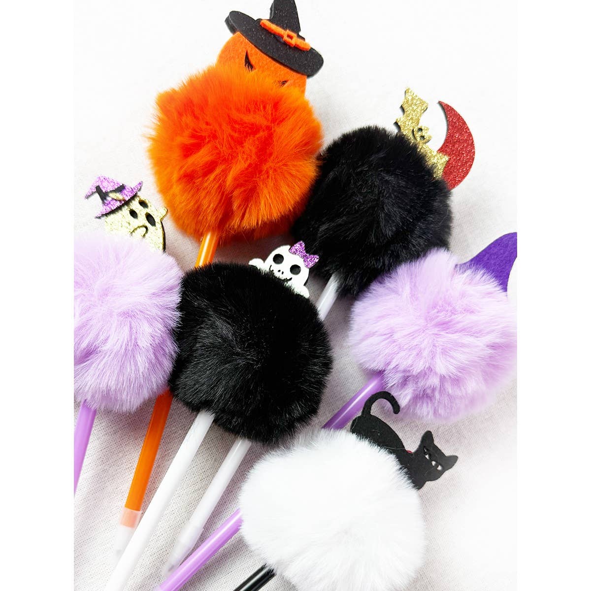 Five Love and Repeat Halloween Theme PomPom Pens topped with colorful pom-poms and Halloween-themed charms, including a witch, a ghost, a cat, and a crescent moon.