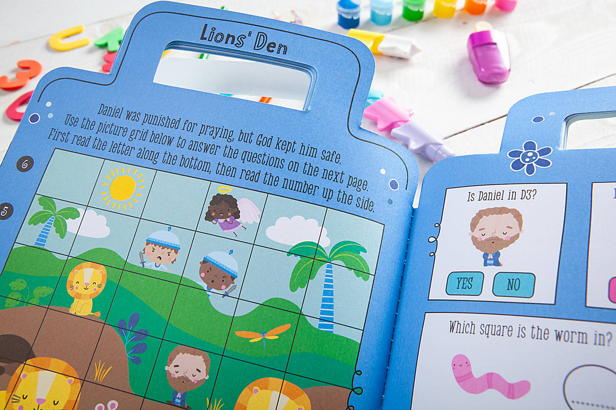 The My Bible Backpack Activity Book by BroadStreet Publishing Group, LLC is open to a vibrant Lions Den puzzle page featuring illustrated people, lions, and a sun with instructions and questions. Colorful toy bears and shapes are scattered around on a white surface.