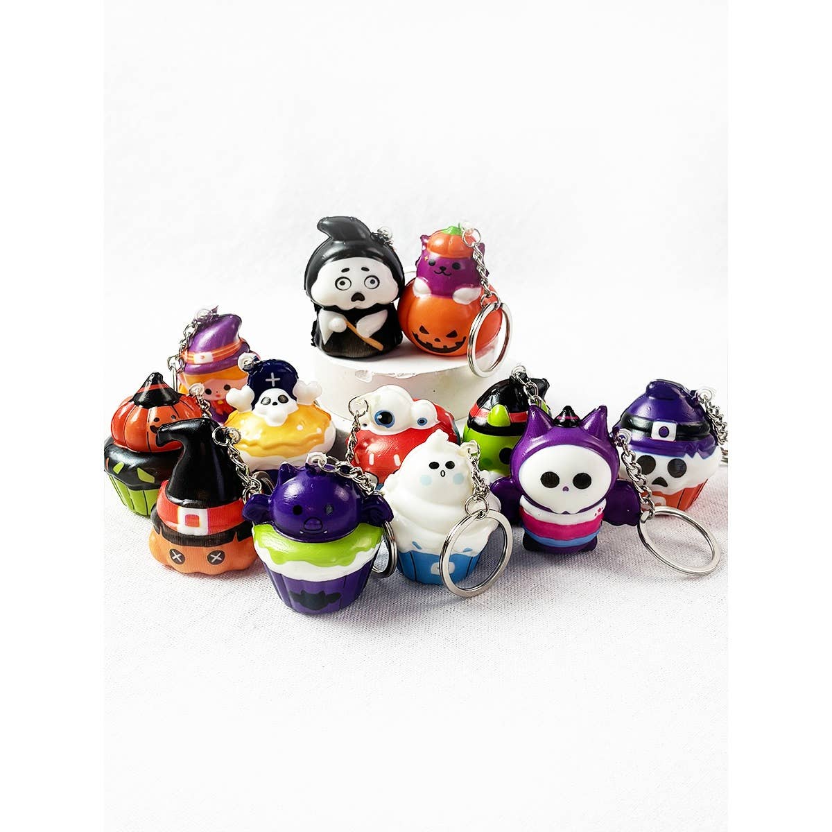 A collection of Love and Repeat Halloween Squishy Keychains shaped like cupcakes, pumpkins, ghosts, and costumed characters.