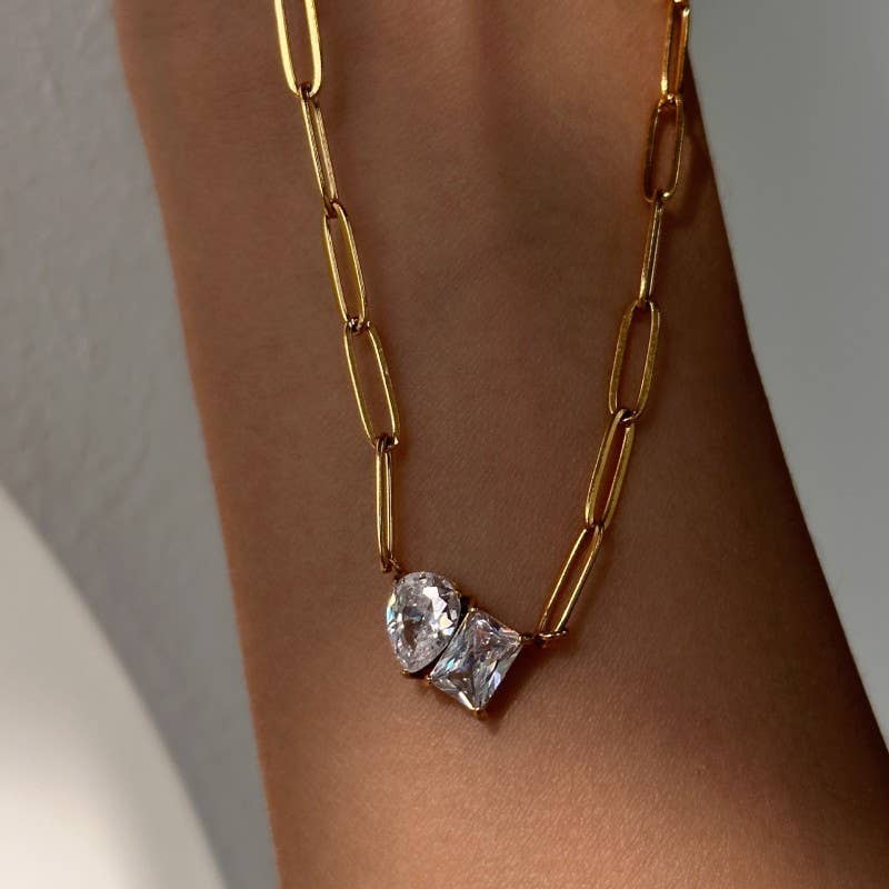 A close-up of the JOSSLYN by wall to wall Gold Rhin Necklace, featuring two clear, asymmetrical gemstones, worn as a bracelet against a softly lit background.