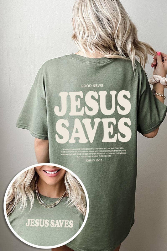 A woman with blonde hair is seen from behind wearing the COLORBEAR Jesus Saves Graphic Heavy Cotton Tee, an oversized green shirt featuring large “JESUS SAVES” lettering and the Bible reference John 3:16-17 on both the front and back.