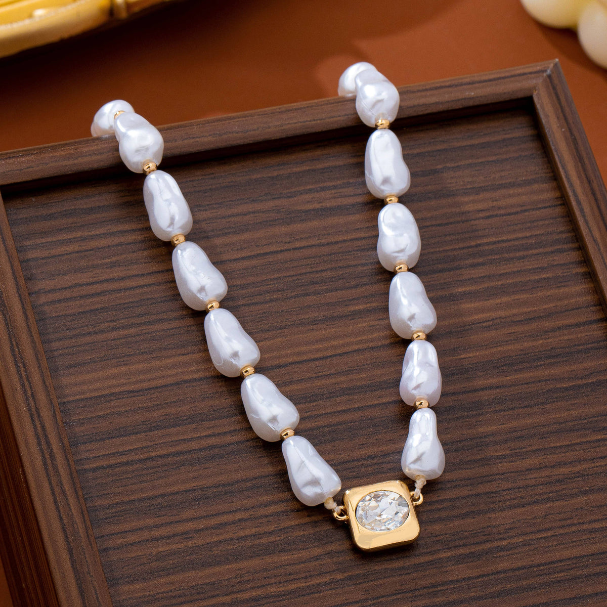 JOSSLYN by wall to wall Baroque Pearl & Bezel-Set Crystal Necklace featuring baroque pearls separated by small gold beads with a square bezel-set crystal pendant.