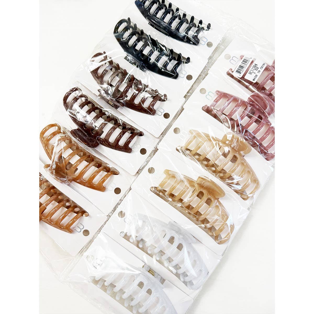 Twelve Love and Repeat Marbled Round Comb Hair Claw Clips in assorted shades of brown, black, white, and beige are neatly arranged on white cards and sealed in clear plastic packaging.