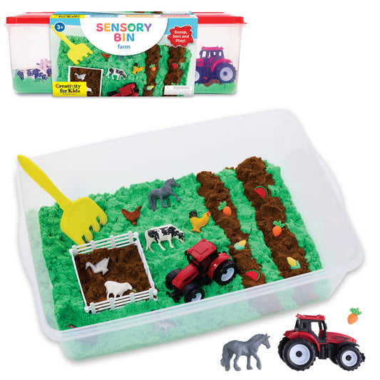 The Faber-Castell / Creativity for Kids Sensory Bin Farm Activity Kit for Kids includes green and brown sensory sand, toy farm animals, a red tractor, a yellow rake, mini carrots, and a white fence—creating an engaging farm scene that inspires children’s imaginative play while helping to develop fine-motor skills.