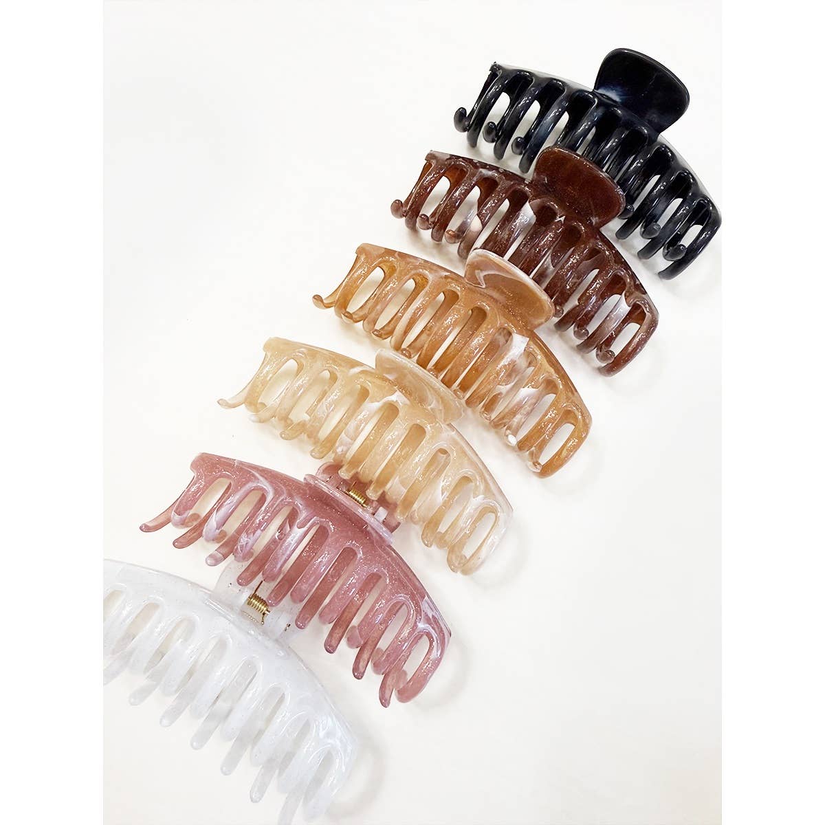 Six Marbled Round Comb Hair Claw Clips by Love and Repeat, featuring a gradient of colors—black, brown, beige, tan, pink, and clear—arranged diagonally on a white background.