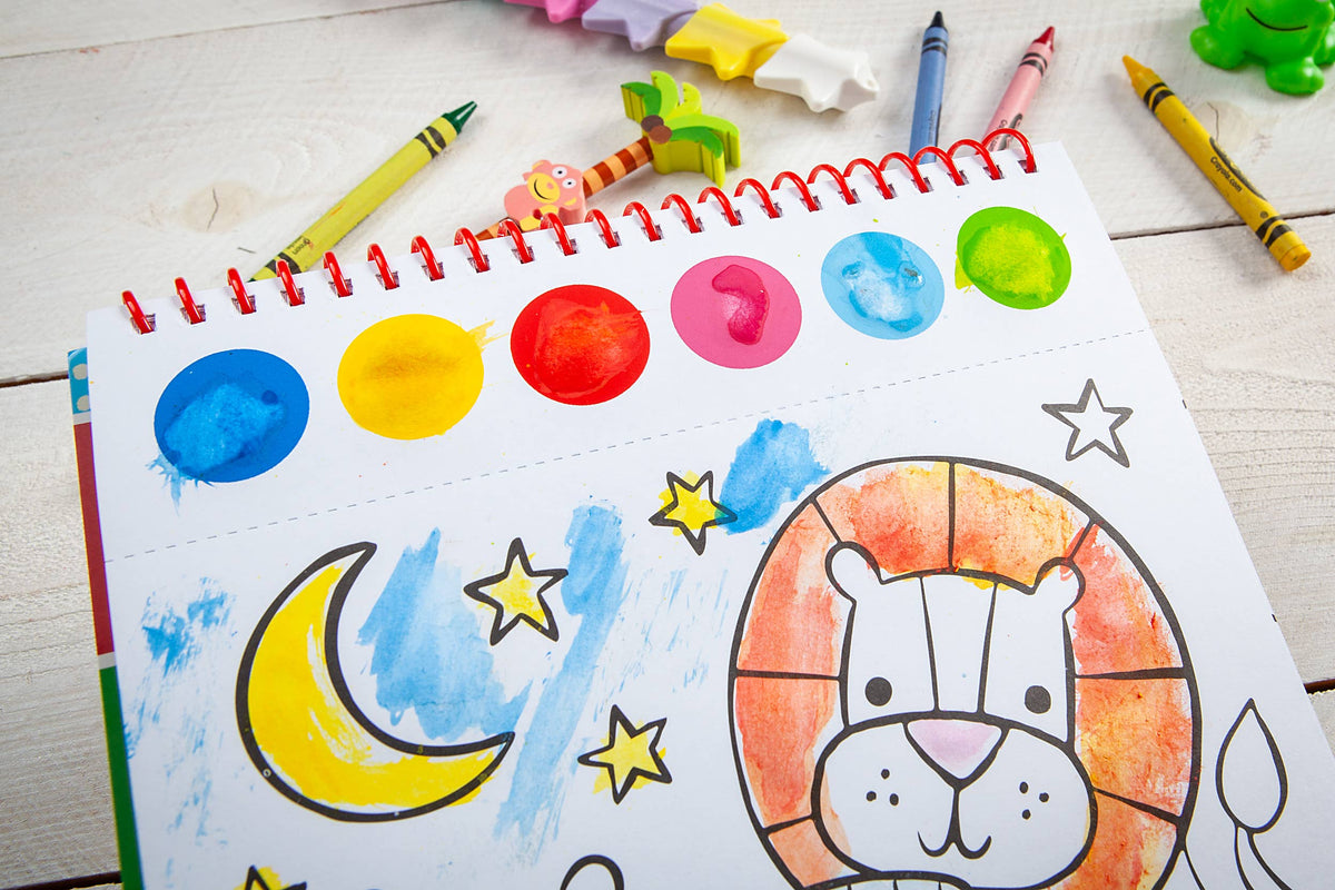 A partially watercolored page featuring a lion with stars and a crescent moon from the Cozy Club Bible Friends Art Pad Book by BroadStreet Publishing Group, LLC sits ready for more creativity, while crayons, painted stars, and toys are scattered across the white wooden table.