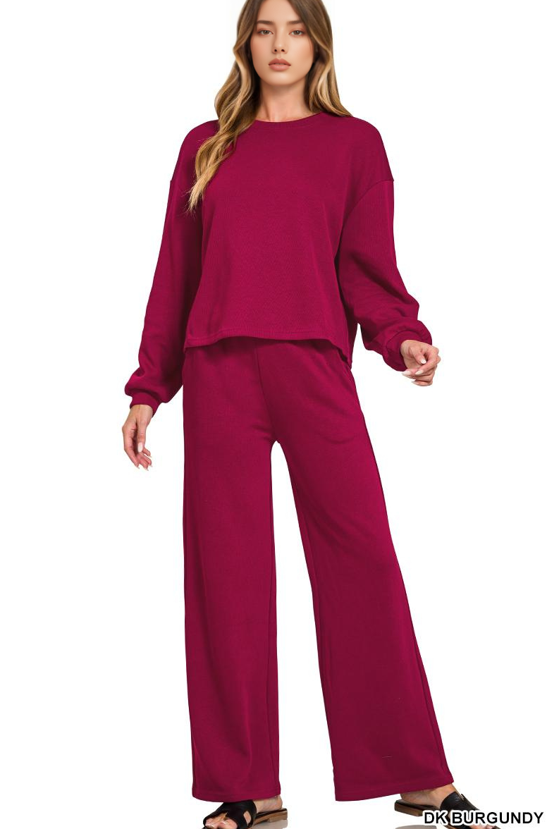 A model wears a Red Ribbed Pullover Pant Set in dark burgundy, featuring a long-sleeved, ribbed pullover top and matching wide-leg trousers.