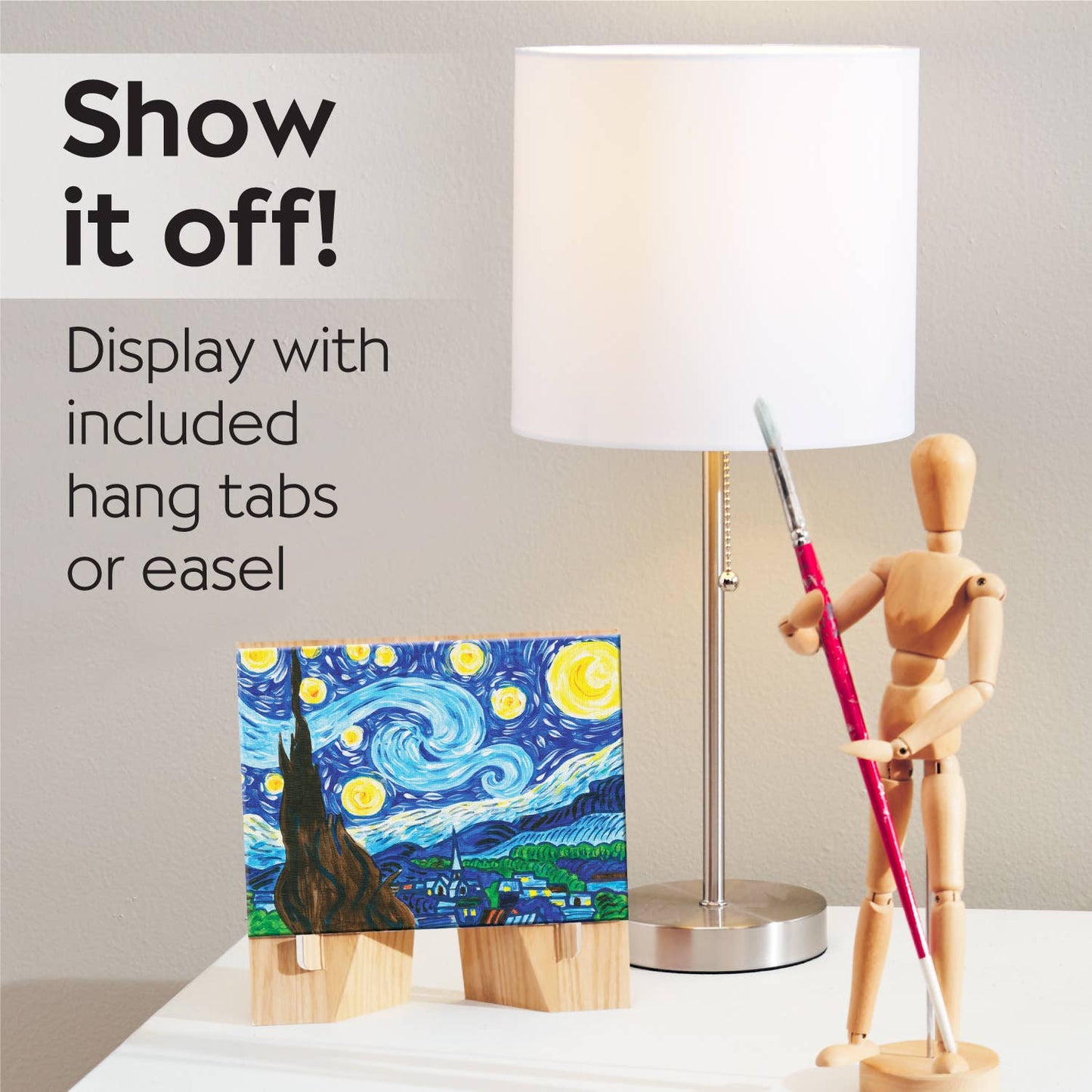A mini canvas of “The Starry Night” from the Paint by Number Museum Series by Faber-Castell / Creativity for Kids is displayed on an easel next to a lamp and a wooden mannequin holding a paintbrush. Ideal for beginner artists, this kit lets you showcase your work with included hang tabs or the easel.