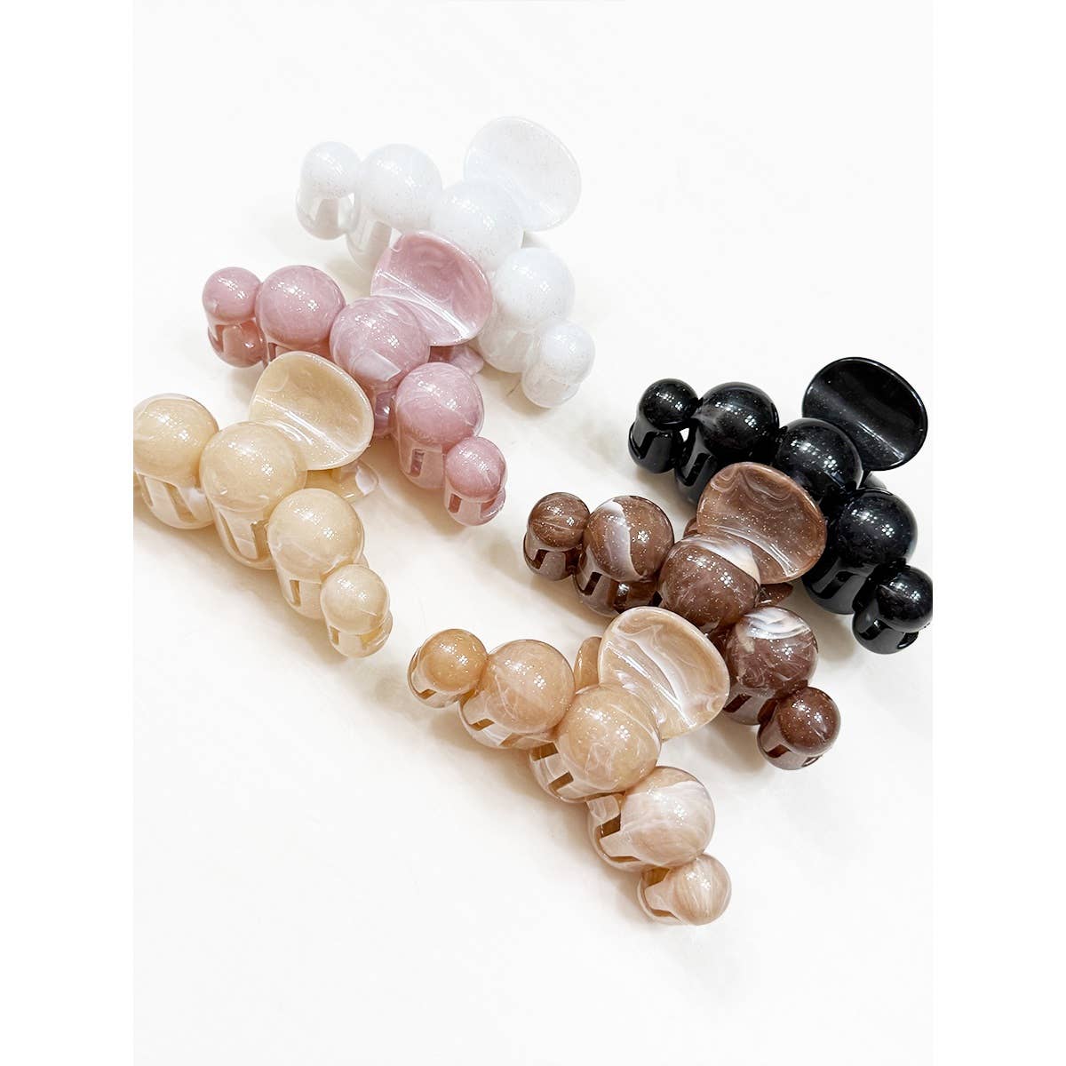 Five Large Marbled Hair Claws by Love and Repeat, in white, pink, black, brown, and beige, are arranged diagonally on a white background.