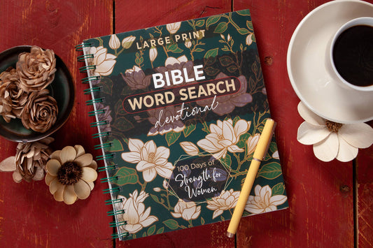 The “100 Days of Strength for Women Word Search Book” by BroadStreet Publishing Group, LLC, featuring a floral cover, is arranged alongside a pen, a cup of coffee, and decorative flowers on a red wooden table.