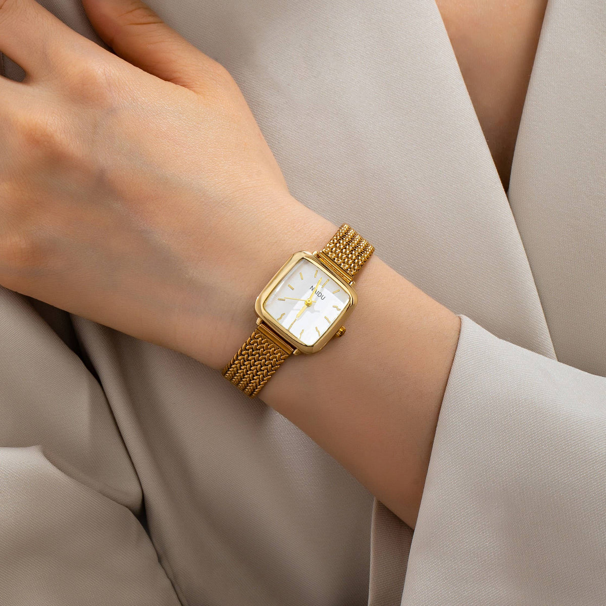 A gold JOSSLYN by wall to wall Square Mesh Band Bracelet Watch with a square face worn on a wrist.