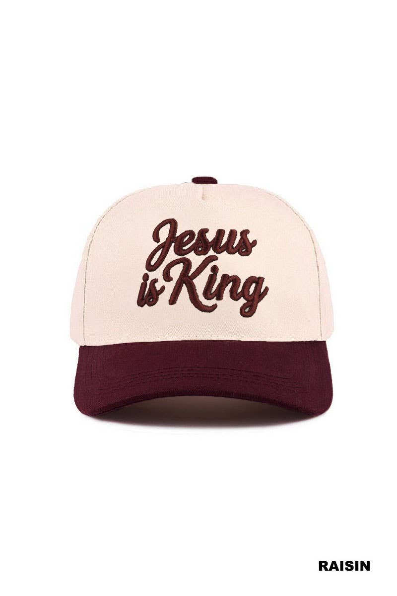 A cream and burgundy Jesus Is King Hat by 42POPS, featuring “Jesus is King” embroidered in brown cursive on the front. The word “RAISIN” appears in the bottom right corner.