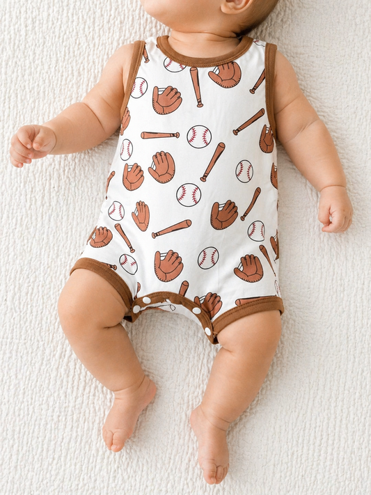 A baby lies on a textured white blanket, wearing Tiny Tot Bundles' Little Slugger Romper—a sleeveless white outfit with brown trim, featuring baseball gloves, bats, and red-stitched baseballs.