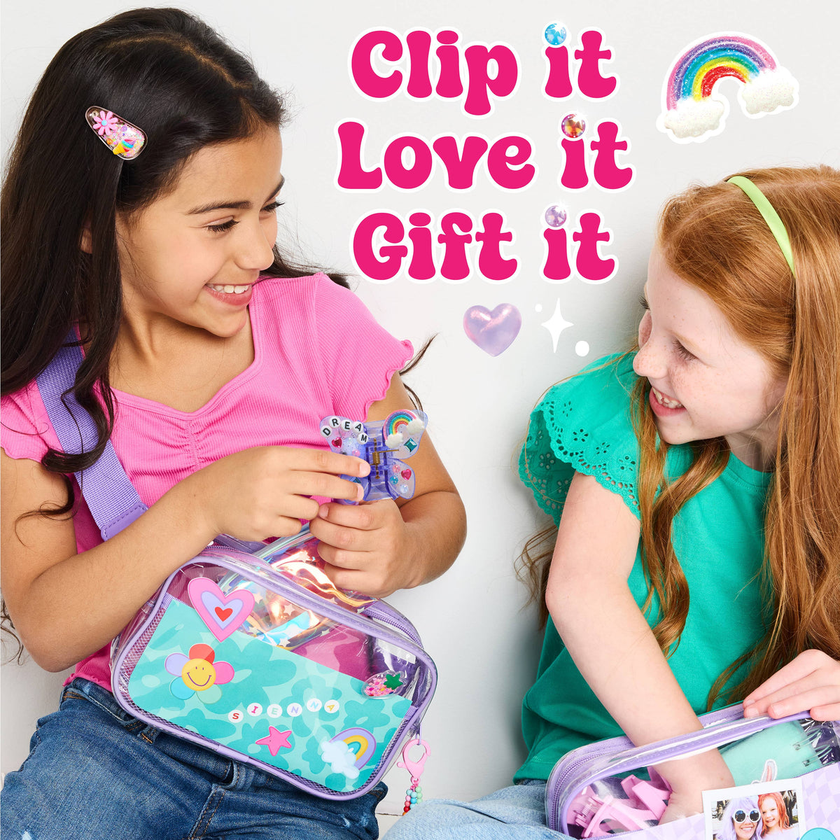 Two young girls ages 6-8 smile and play with the Chic Boutique DIY Hair Clip Kit for Kids by Faber-Castell / Creativity for Kids, surrounded by colorful accessories and clear bags. Text reads, Clip it, Love it, Gift it. Butterfly claw clips add a playful touch, while rainbow, sparkles, and heart graphics decorate the scene.