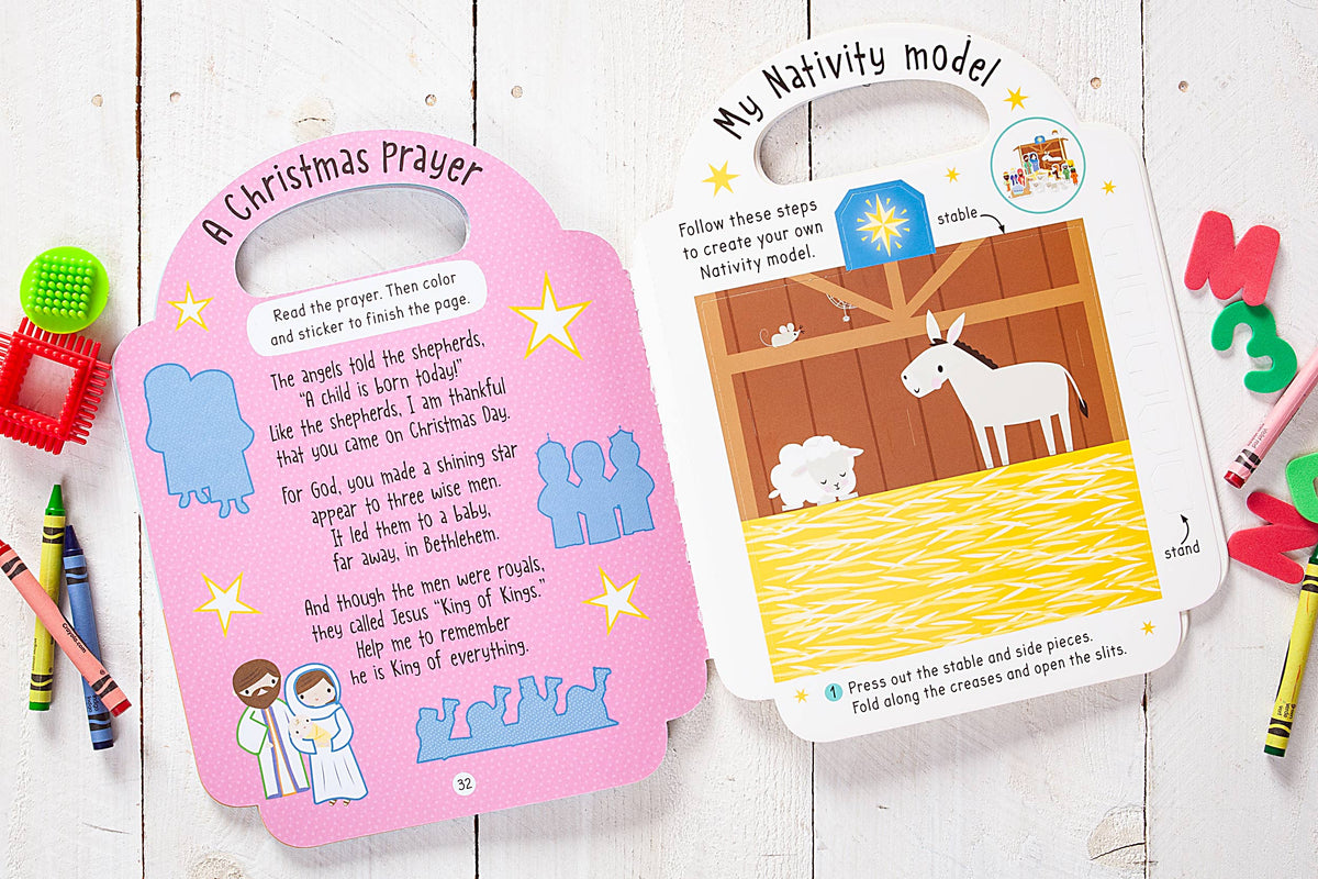 An opened copy of *The Story of Christmas Activity Book* by BroadStreet Publishing Group, LLC displays a prayer alongside drawings of shepherds, Mary, and Joseph on one page, with a Nativity scene featuring a donkey and sheep on the opposite page, plus craft instructions.