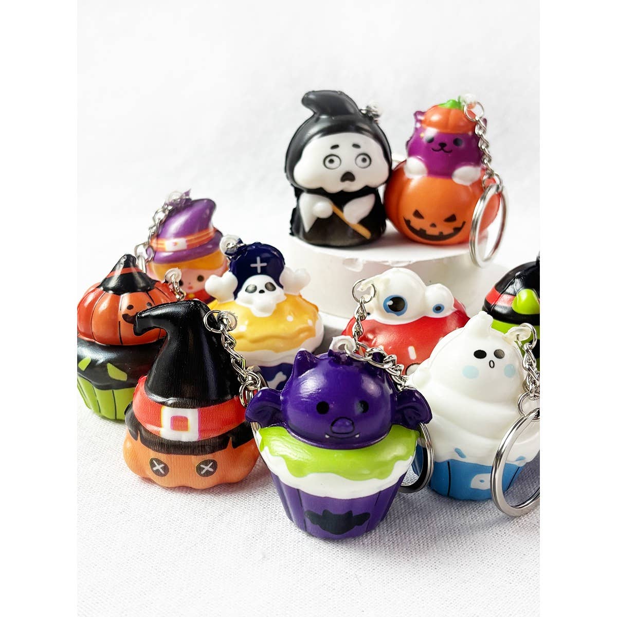 A collection of colorful Halloween Squishy Keychain designs shaped like cupcakes, including ghost, pumpkin, witch, and bat themes.