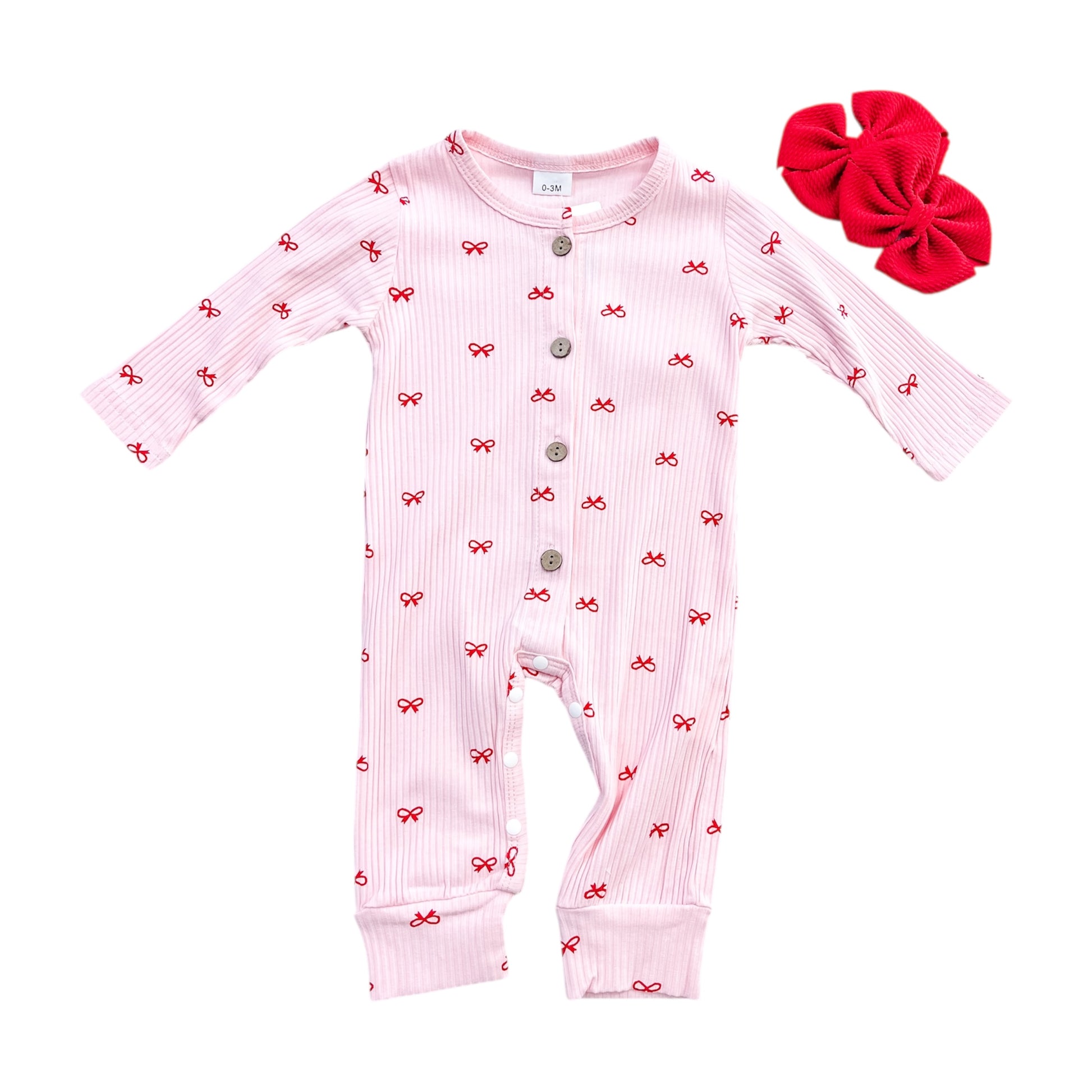 Tiny Tot Bundles' Tiny Bows Ribbed Romper features pink ribbed fabric with small red bows and front buttons, paired with a large red bow headband, shown together on a white background.