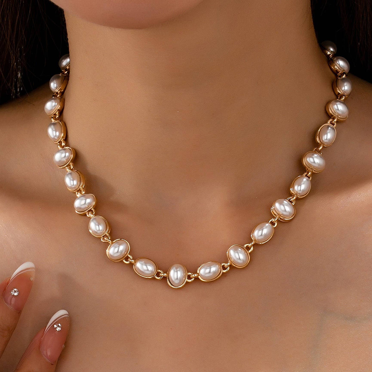 A JOSSLYN by wall to wall Oval Pearl Link Necklace composed of oval pearls set in gold-tone metal links worn around a person’s neck.