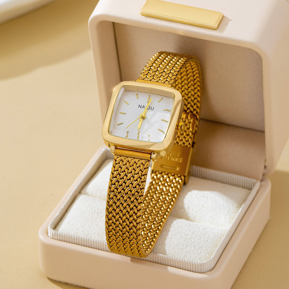 JOSSLYN by wall to wall Square Mesh Band Bracelet Watch in gold-tone with a woven mesh band, resting in an open cream jewelry box.