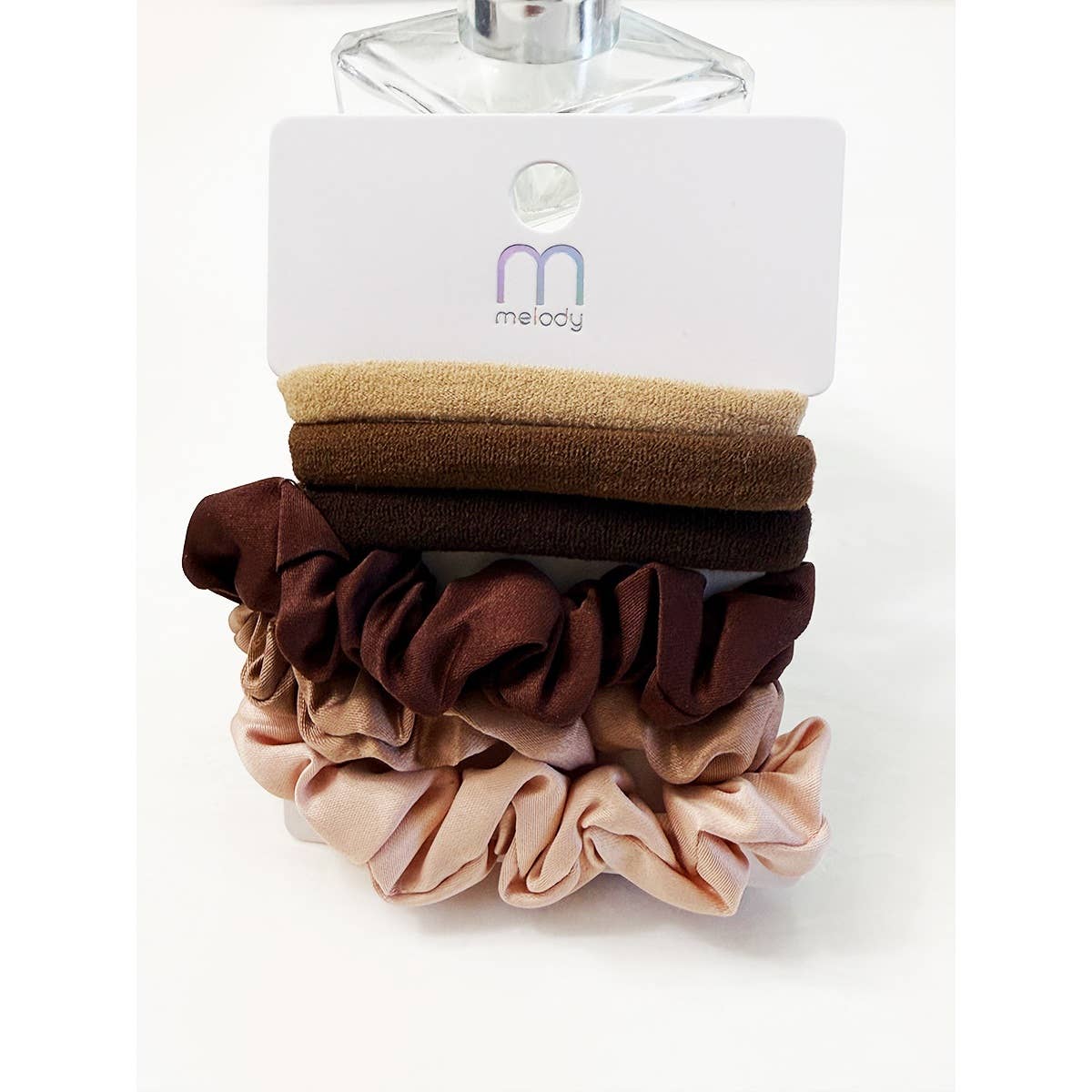 Five hair scrunchies in assorted shades of brown and beige are displayed on a white card labeled Love and Repeat, featuring the Assorted Hair Tie & Scrunchie Set.