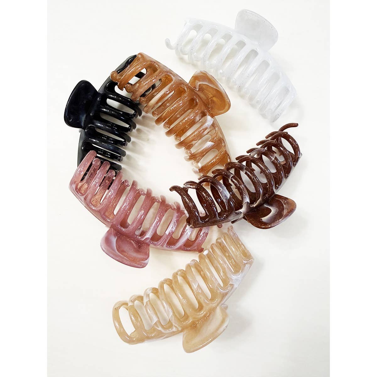 Six Marbled Round Comb Hair Claw Clips by Love and Repeat, featuring assorted neutral tones, are arranged in a circular pattern on a white background.