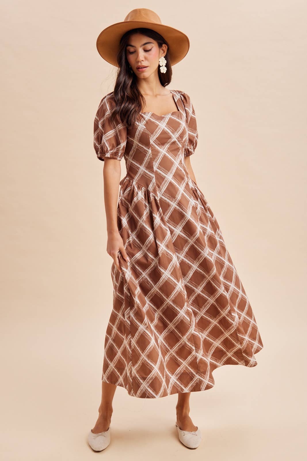 A woman wearing an In Loom Plaid Square Neck Maxi Dress in brown with a white plaid pattern, a wide-brim hat, and flats.