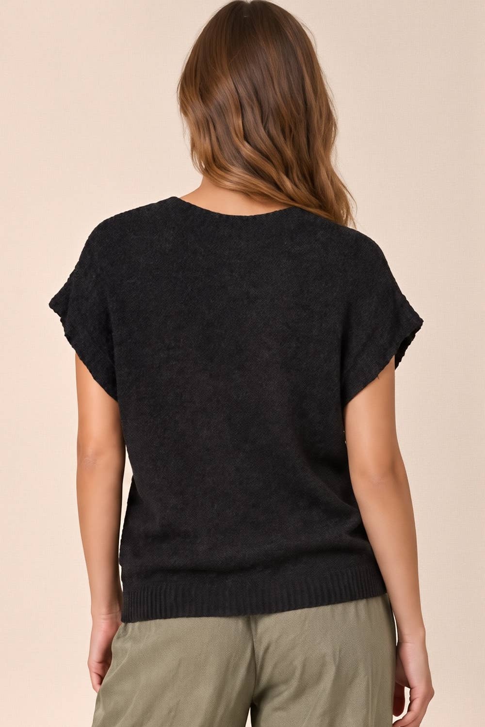 Back view of a person wearing a Black Knit Sweater Top featuring a short-sleeved black knit design with a ribbed hem.