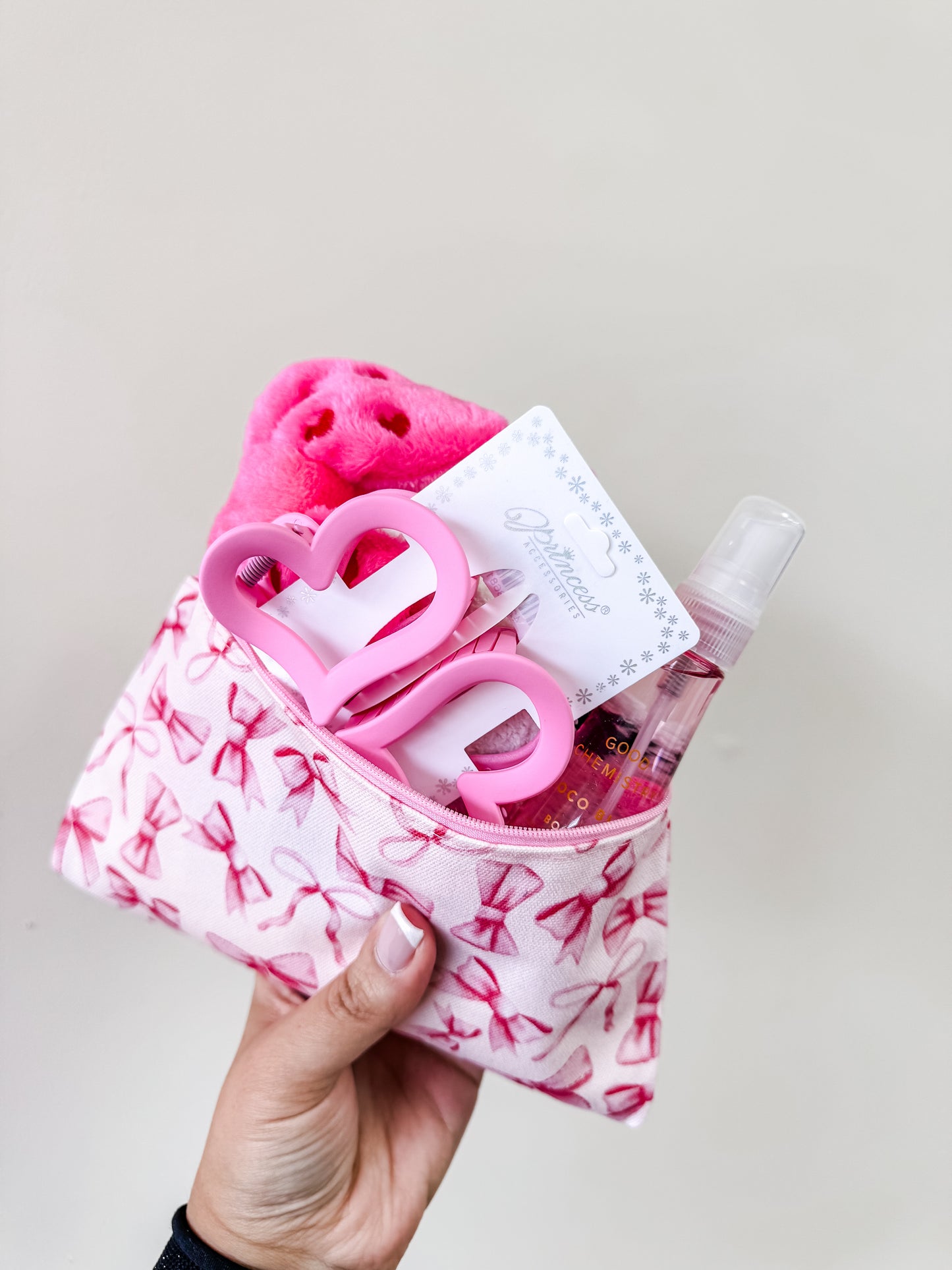 A hand holds the Coquette Valentine’s Girl Bundle by Tiny Tot Bundles, featuring a pouch with ballet slipper designs, pink accessories, Good Chemistry Body Mist, and a card, set against a plain light background.