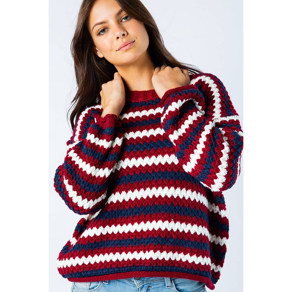 Woman wearing a Sweet Generis Chunky Knit Multi Color Sweater featuring horizontal zigzag stripes in red, white, and navy blue.