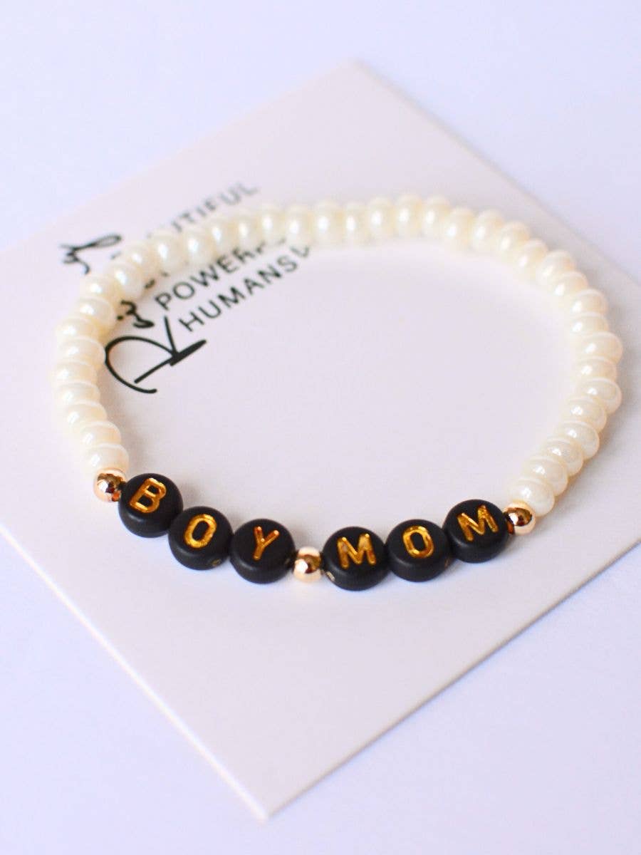 The Boy Mom Pearl Bracelet by Two and Crew - Faith Based Jewelry & Gifts features white pearls and black beads that spell out BOY MOM in gold letters, elegantly displayed on a white card.