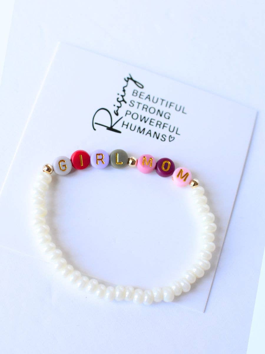 The Girl Mom Beaded Bracelet by Two and Crew - Faith Based Jewelry & Gifts features white beads and colorful letter beads that spell out GIRL MOM. It comes displayed on a card with the message, “Raising beautiful, strong, powerful humans.”.