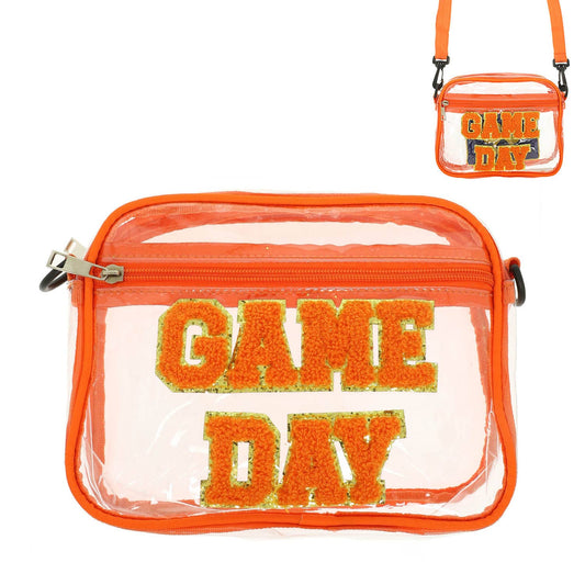 The SP Sophia Collection “Game Day” Clear Bag features bold orange and yellow GAME DAY lettering on the front, stylish orange trim, a convenient zipper closure, and an adjustable orange strap. Shown in detailed close-up and full product views.