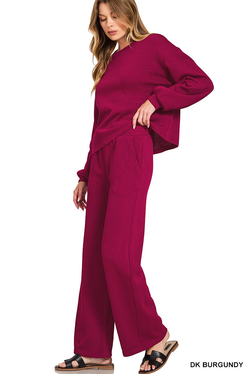 A woman wearing a dark burgundy Red Ribbed Pullover Pant Set featuring a long-sleeved ribbed pullover and matching wide-leg trousers.