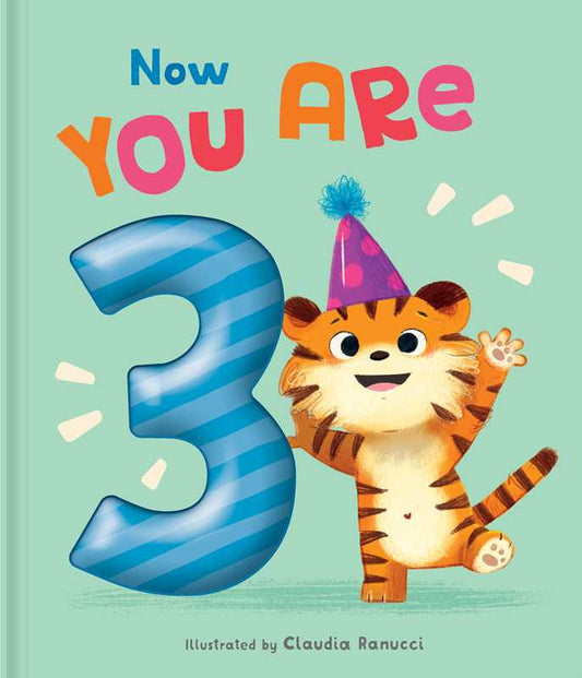 A cheerful cartoon tiger in a purple party hat stands by a blue striped number 3 with "Now You Are 3" above, set on light green. From Simon & Schuster, the Now You Are 3 Book celebrates their big day!.