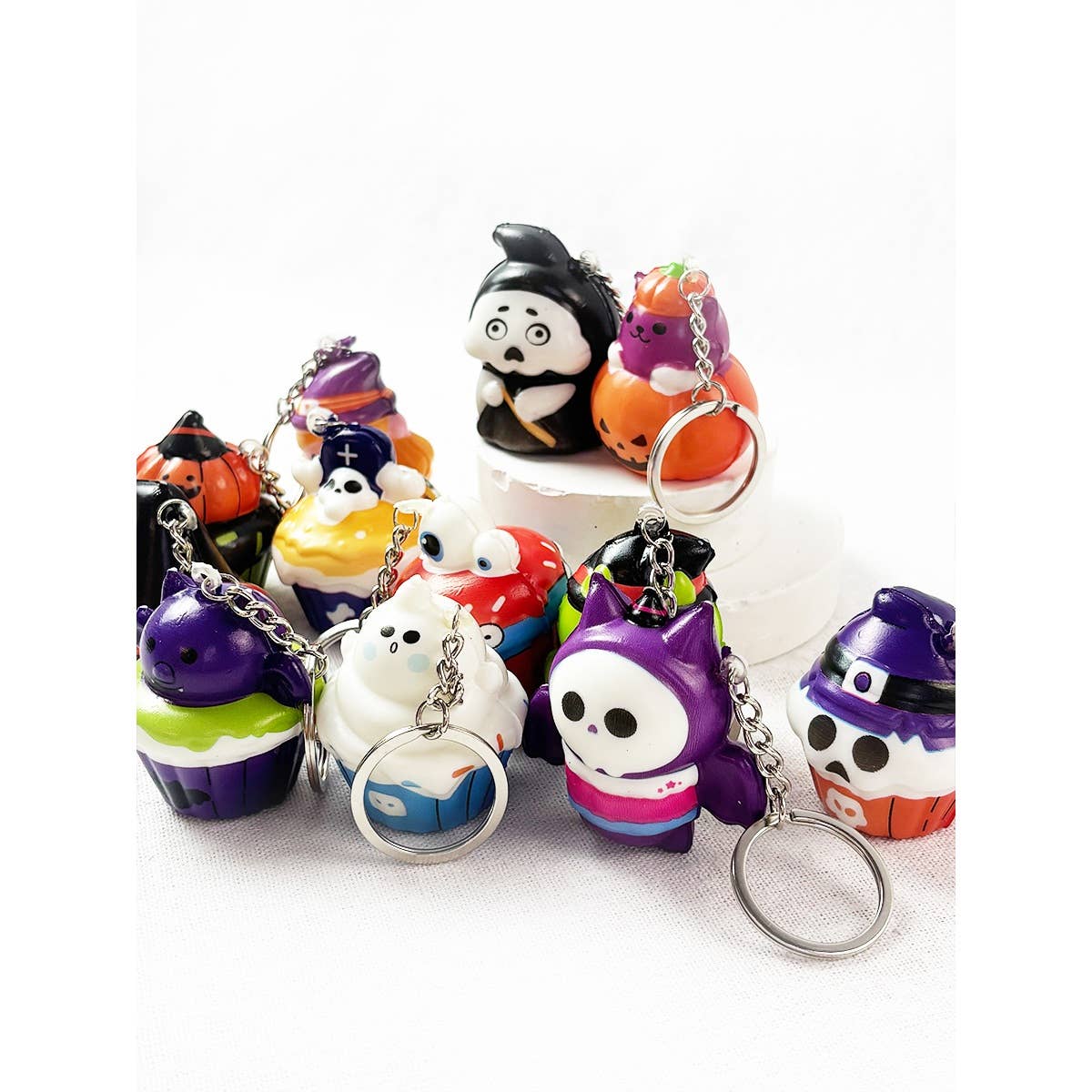 A collection of Halloween Squishy Keychain toys shaped like cupcakes, ghosts, and figures wearing costumes.