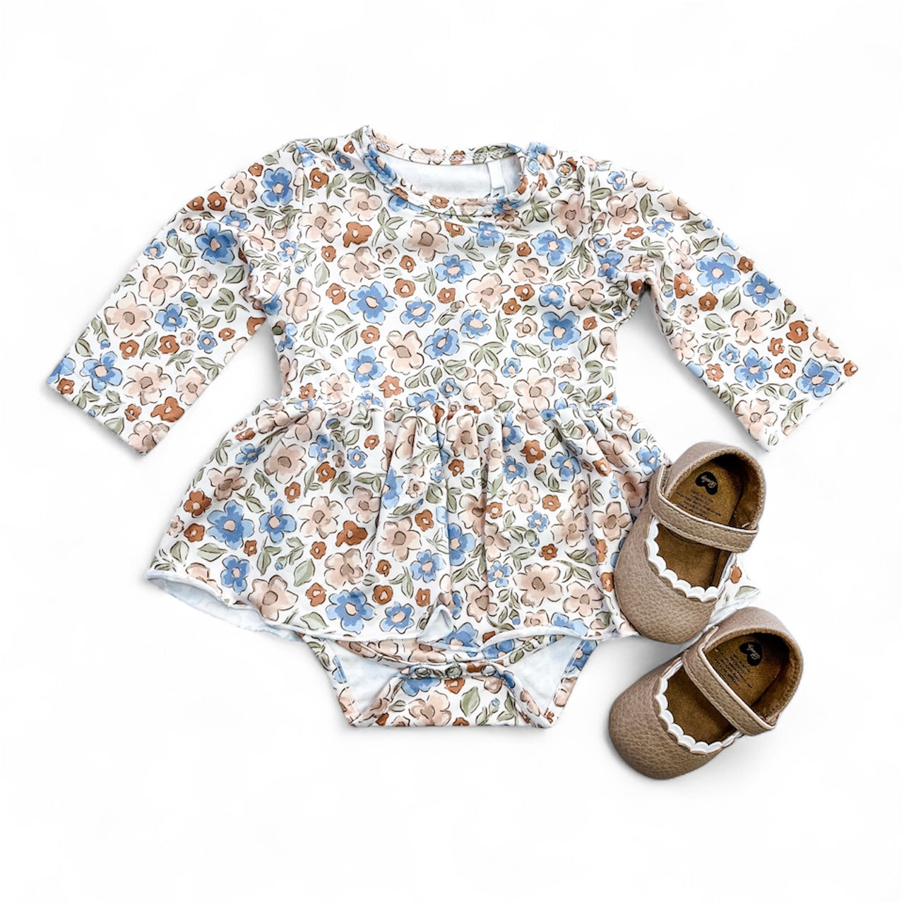 The Tiny Tot Bundles Wildflower Whisper Longsleeve Twirl Romper in pastel floral print is shown with brown baby shoes with white scalloped trim, all displayed on a white background.