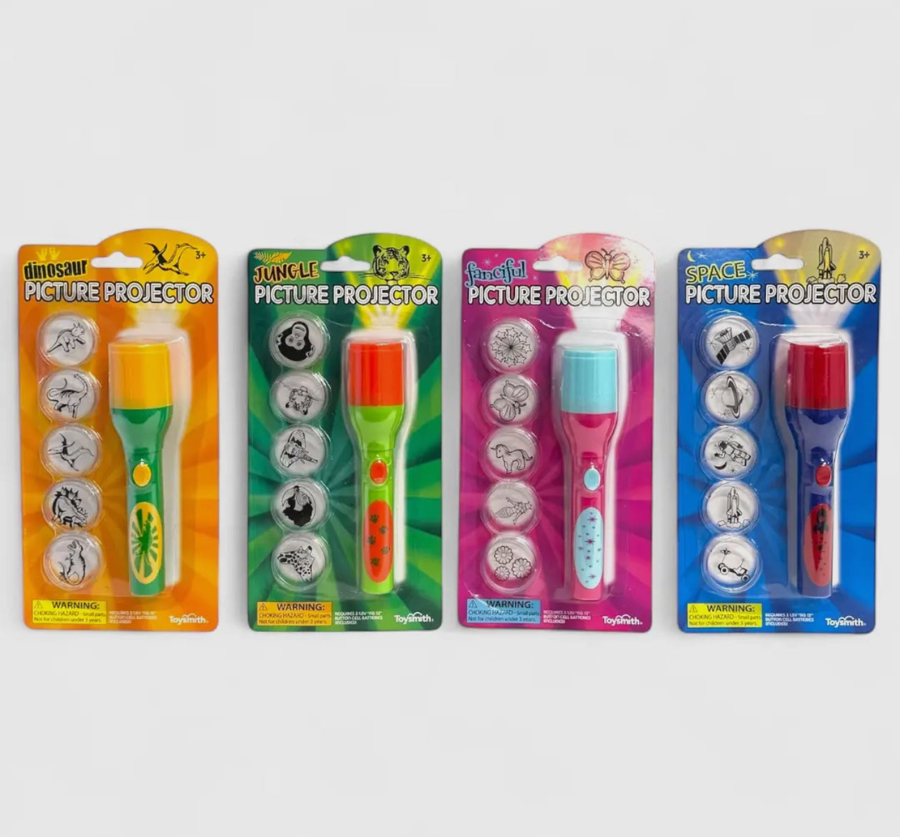 The Toy Smith Mini Led Projector comes in four colorful packages—dinosaur, jungle, fairy-tale, and space themes. Each includes three image disks with related black-and-white illustrations. Packaging is labeled for each theme.