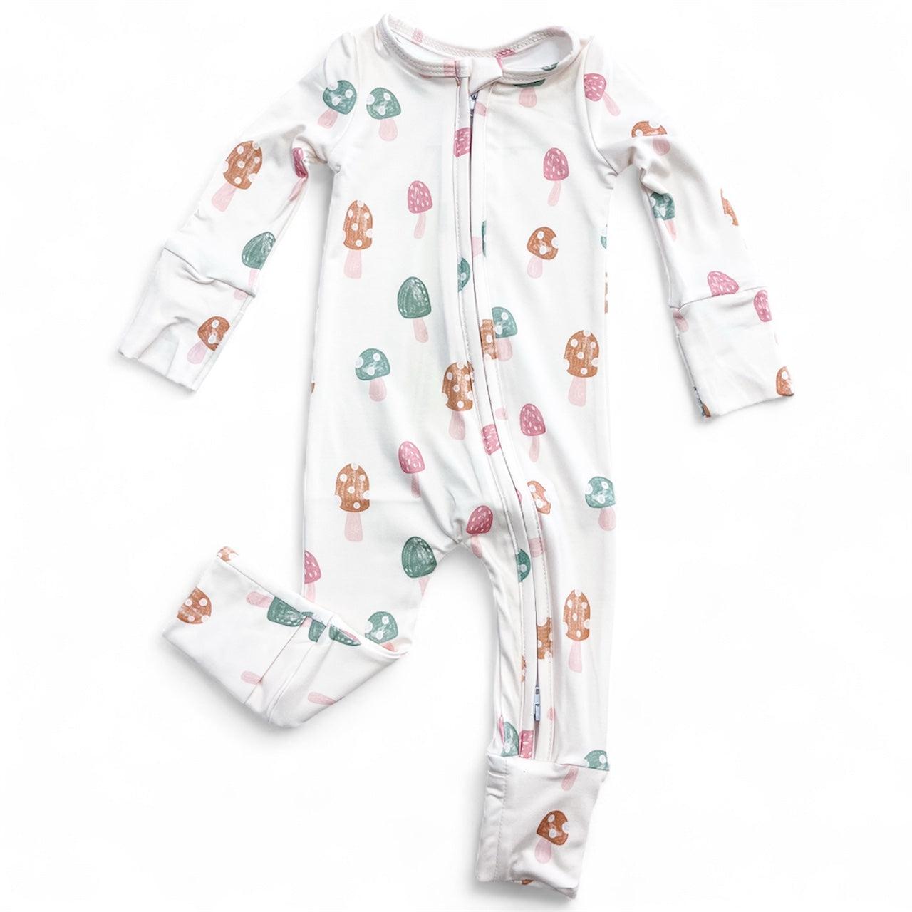 The Tiny Tot Bundles Mushroom Meadow Zippy is a white baby onesie with long sleeves and legs, featuring pink, green, and brown mushroom patterns, a front zipper, and cuffed wrists and ankles.
