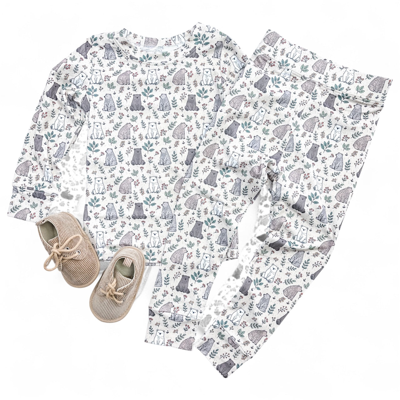The Tiny Tot Bundles Woodland & Friends Jammies Set features a forest animal and plant print long-sleeve top with matching pants, shown alongside beige lace-up corduroy shoes, all displayed on a white background.